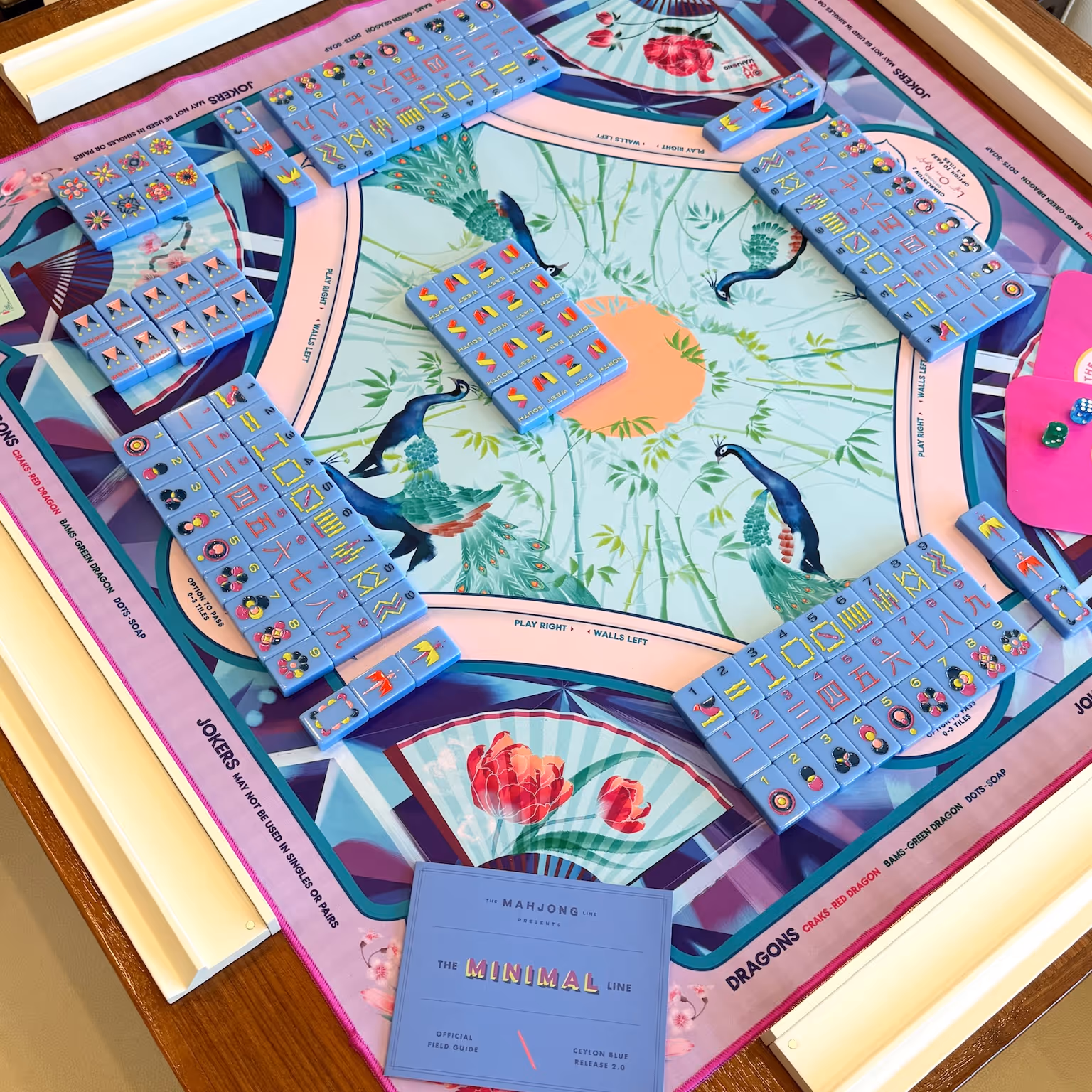 A fully set American mahjong table from above — the patterned Mahjong Standard mat, four racks of tiles and the wall built, ready to play