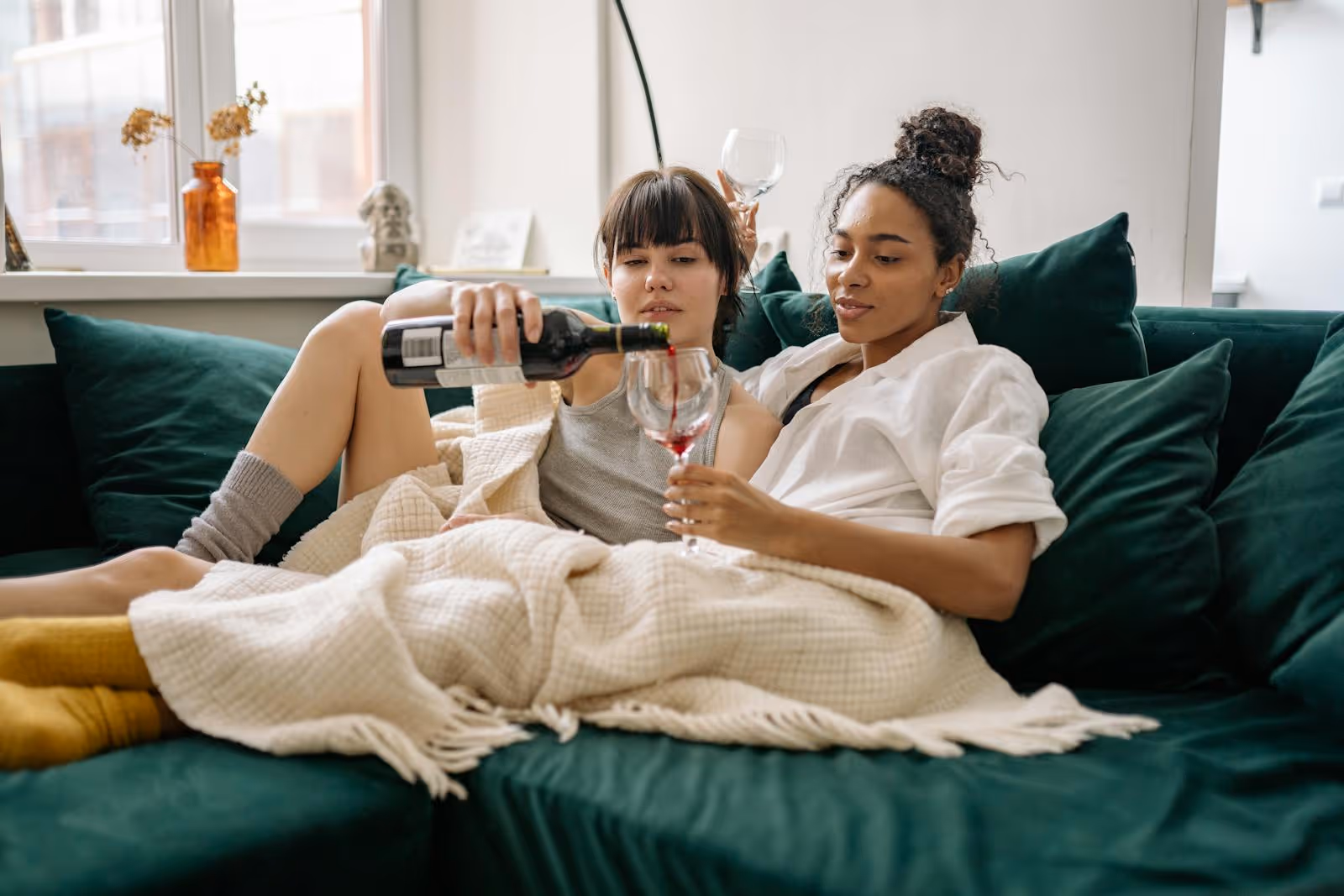 Two women relaxing together with a glass of wine at home