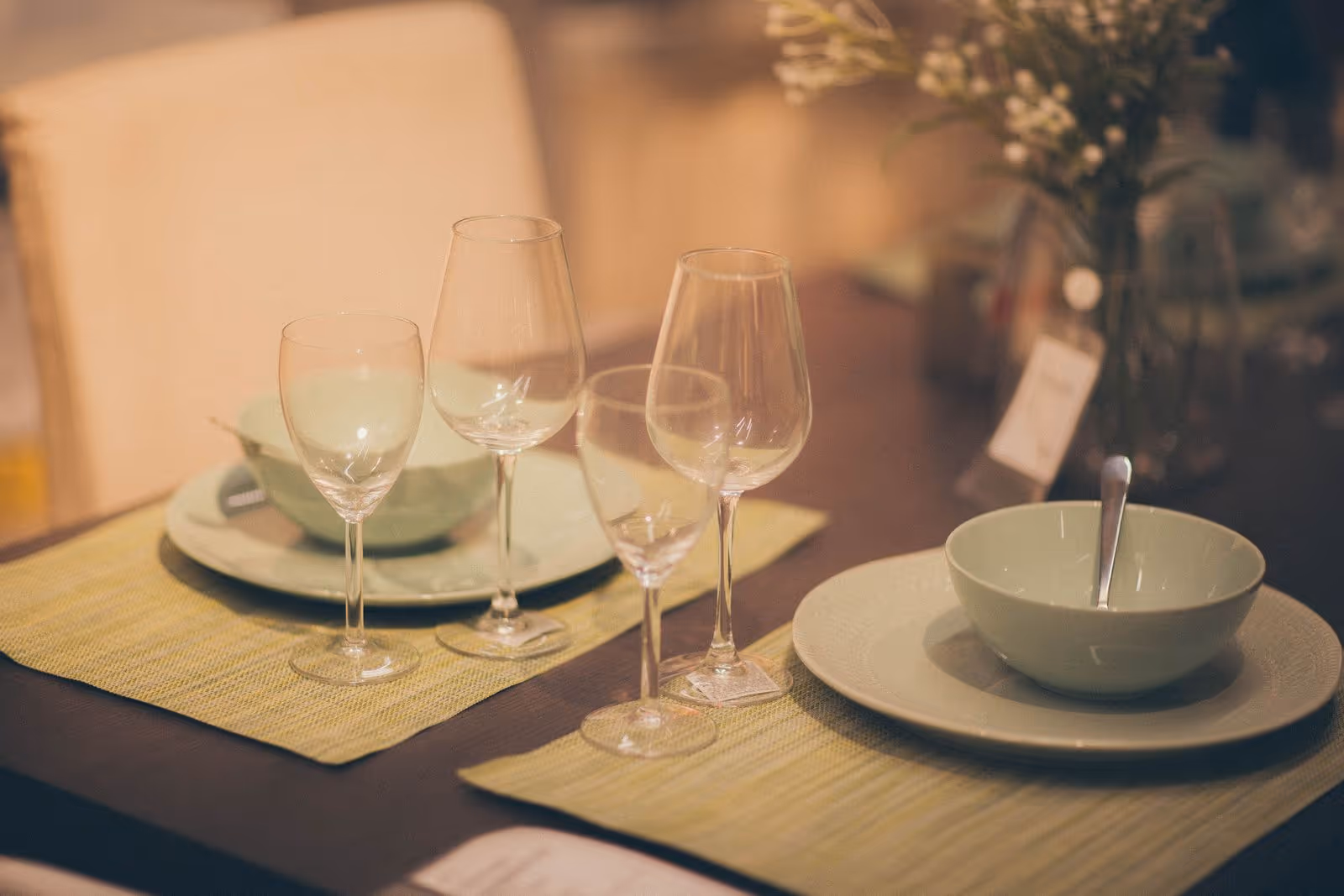 A table set with celadon bowls and bamboo placemats in warm light