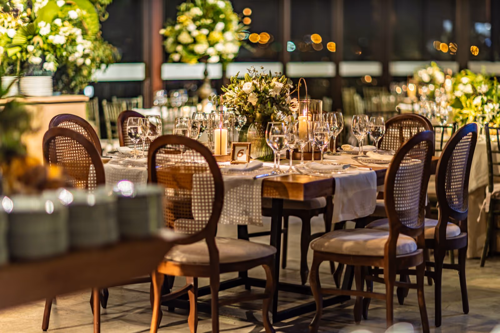 An inviting outdoor evening gathering, tables set among florals