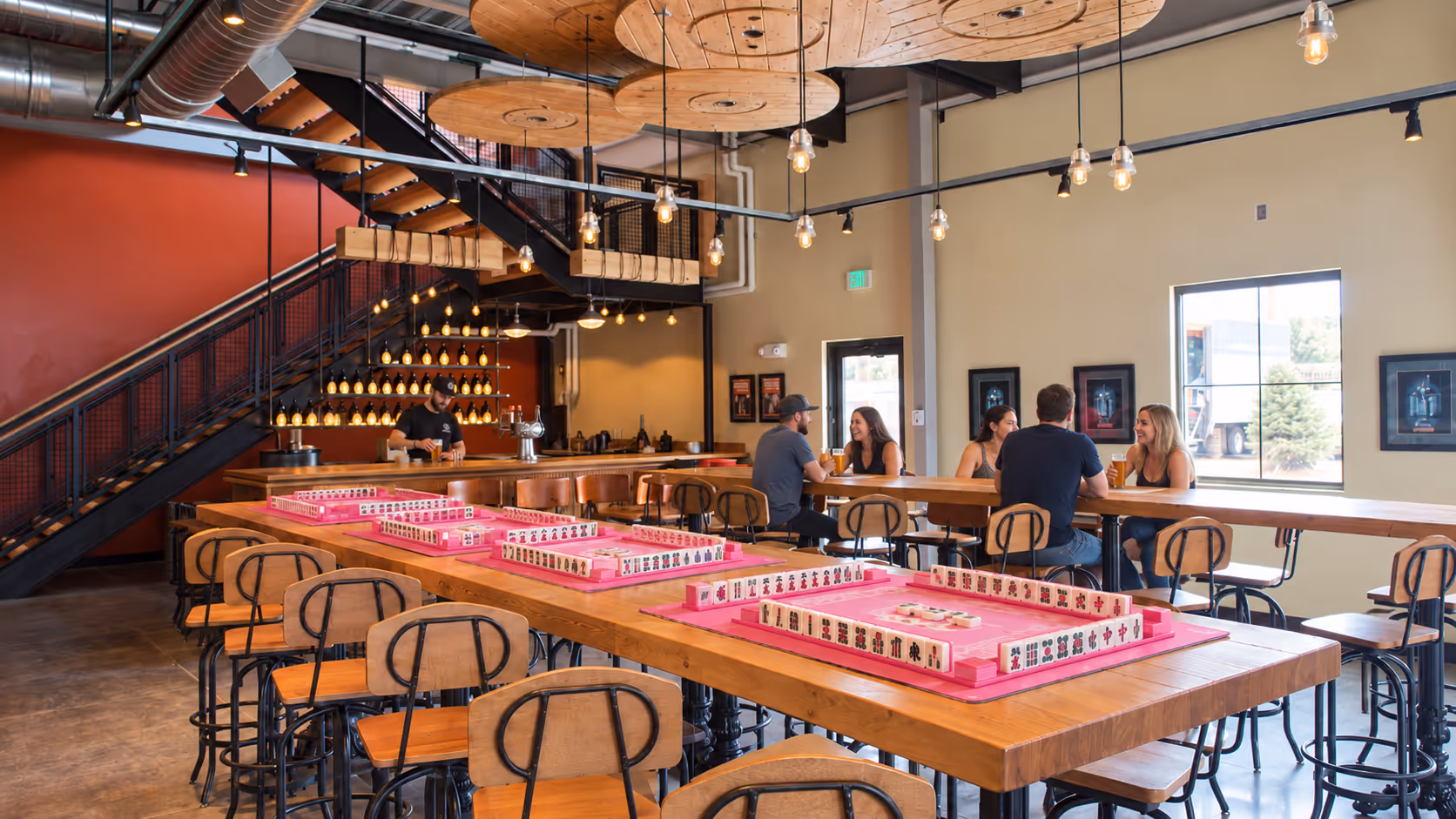 The long taproom at Breckenridge Brewery in Littleton, warm pendant lights and reclaimed-wood tables, the setting for the November 19 couples mahjong night
