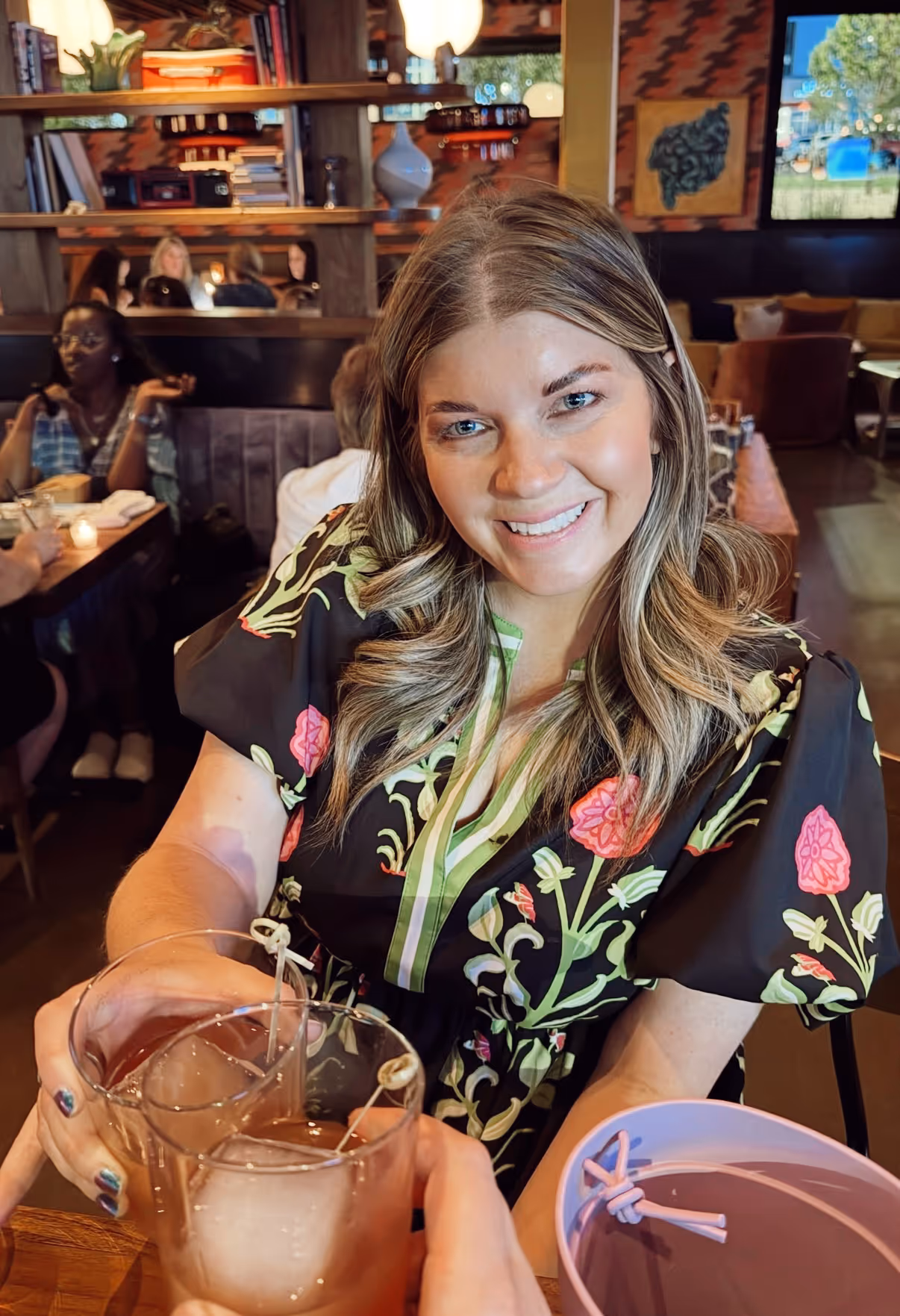 Courtney Colclough, founder of Mahjong Standard, smiling warmly at the camera, raising a glass with friends at an evening out