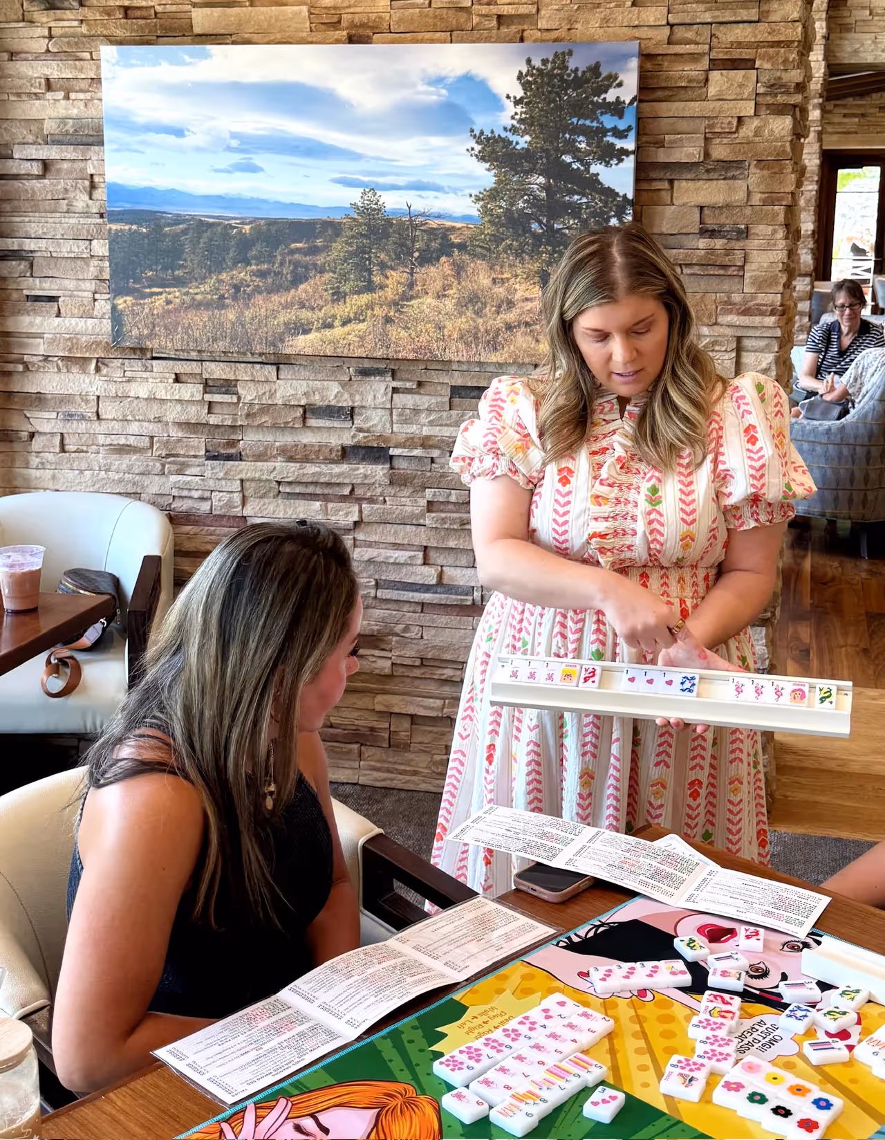 Courtney, founder of Mahjong Standard, setting up her tile rack at a sunlit table set with a colorful mahjong mat