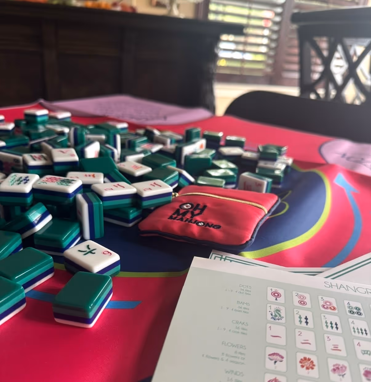 An outdoor mahjong table set for play with a group gathered behind it