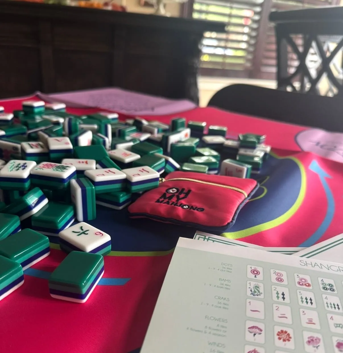 An outdoor mahjong table set for play with a group gathered behind it