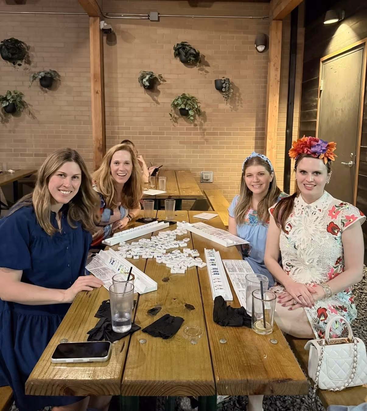 Four friends around a table together, laughing, after an afternoon of mahjong