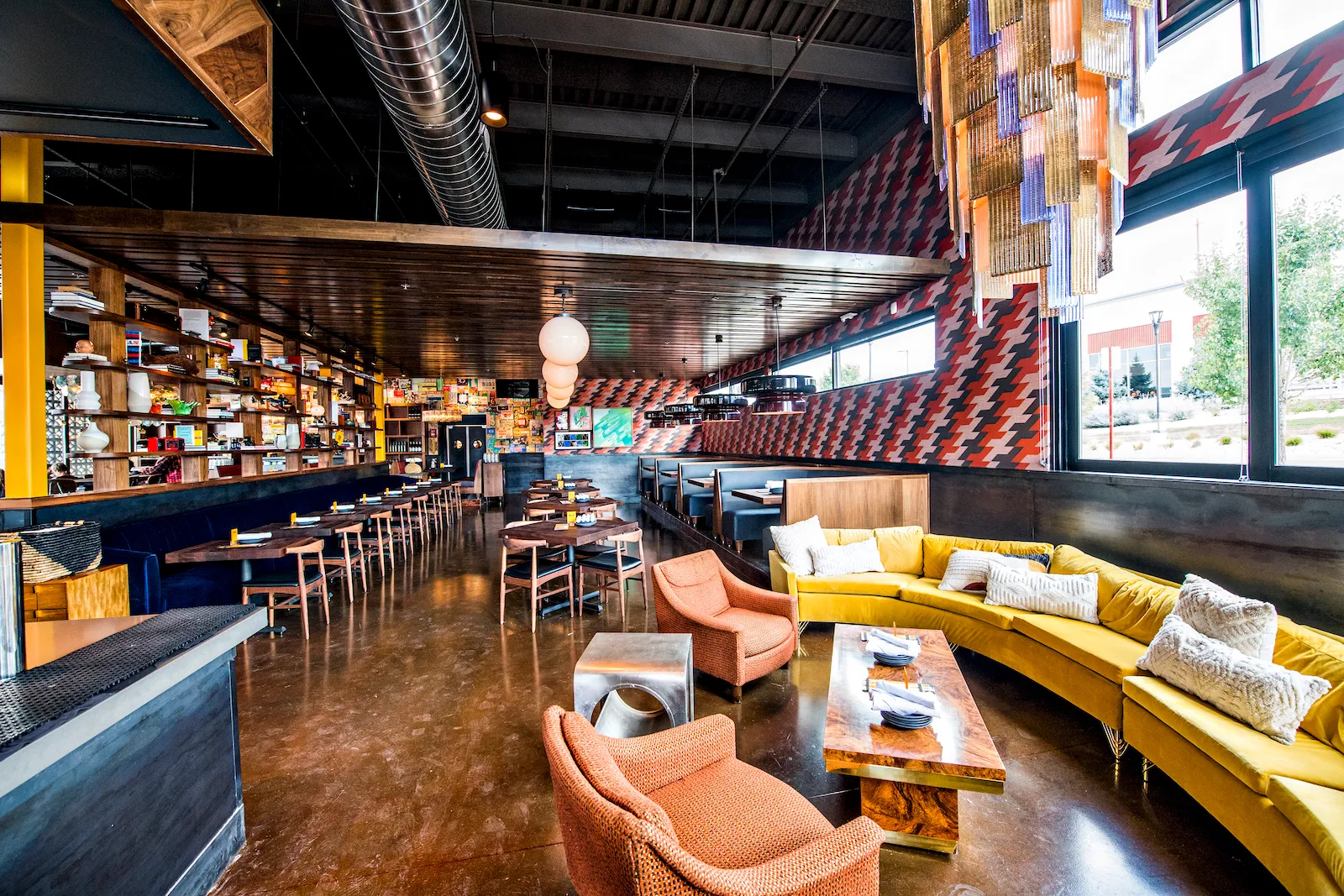 Inside Postino in Highlands Ranch, warm wood, a long bar and a curved golden-yellow banquette in the sunlit lounge