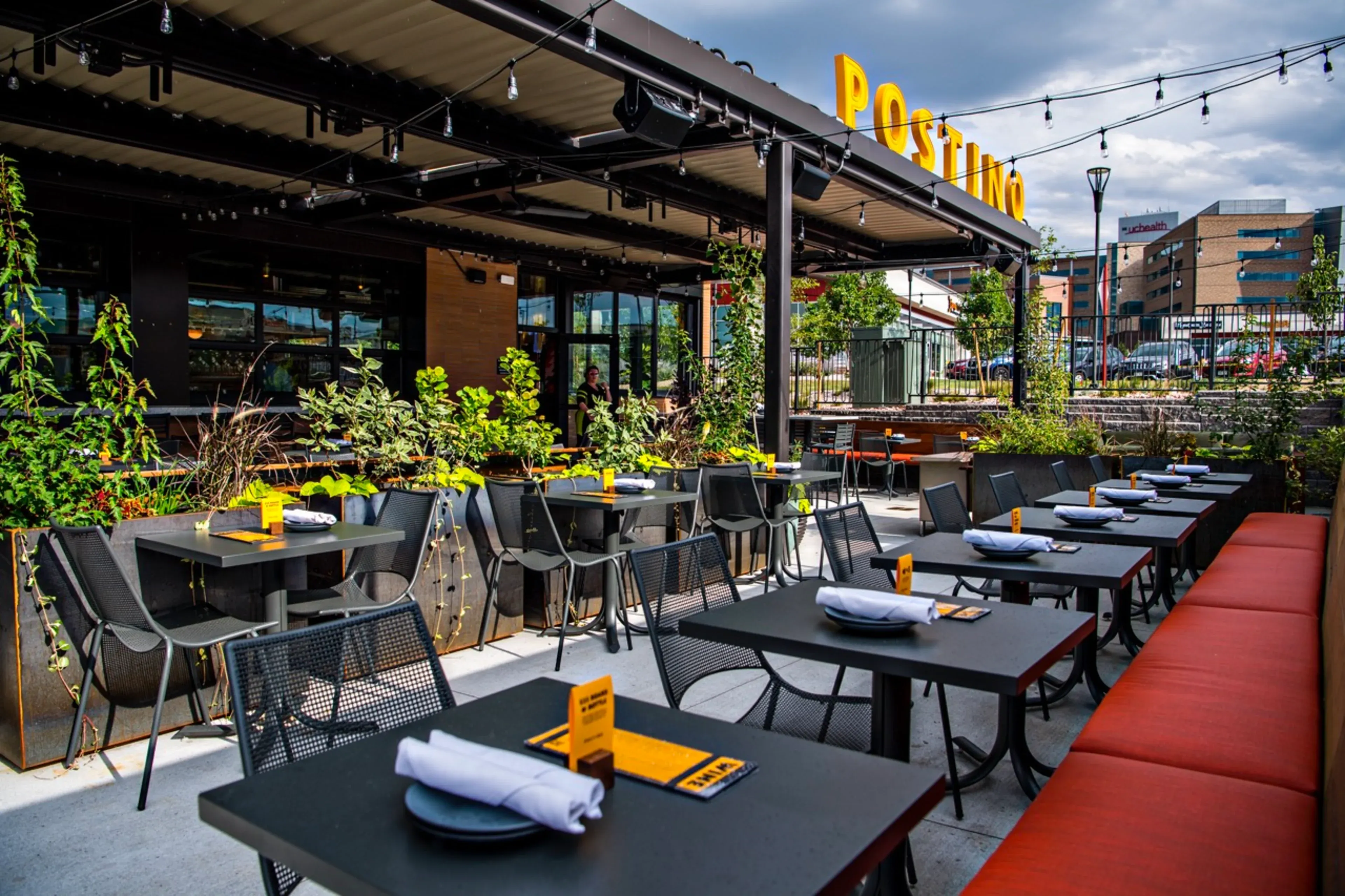 The covered patio at Postino in Highlands Ranch strung with lights beneath the gold POSTINO sign, tables set for the evening