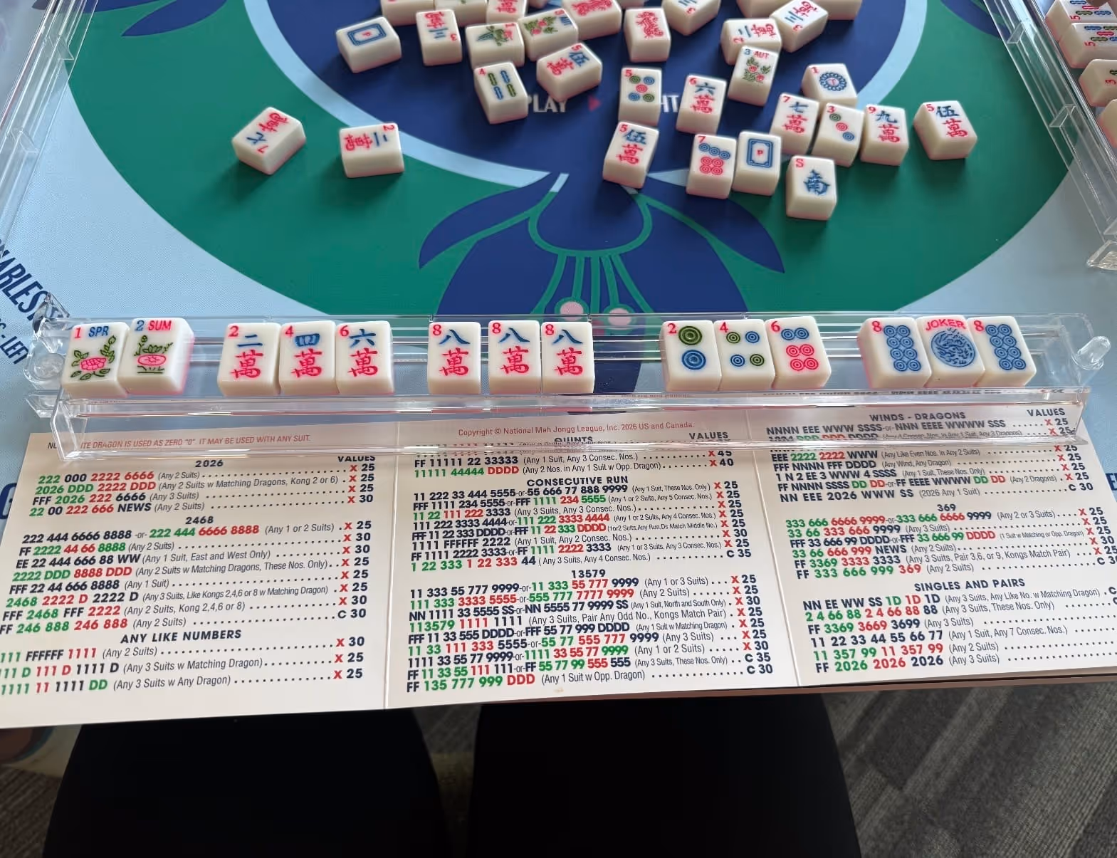 A full American mahjong table from above — mat, four racks of tiles and the card, set for a game