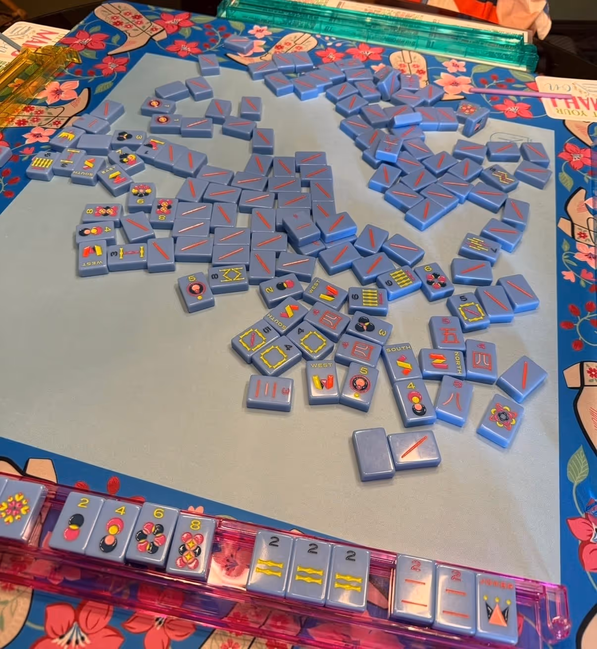 A mahjong table set up at home — mat, racks, tiles and the American mahjong card, ready to play