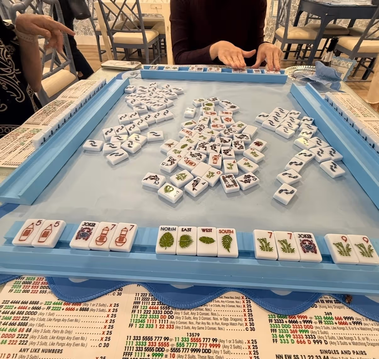 Mahjong tiles racked and ready on a warm wooden table at home