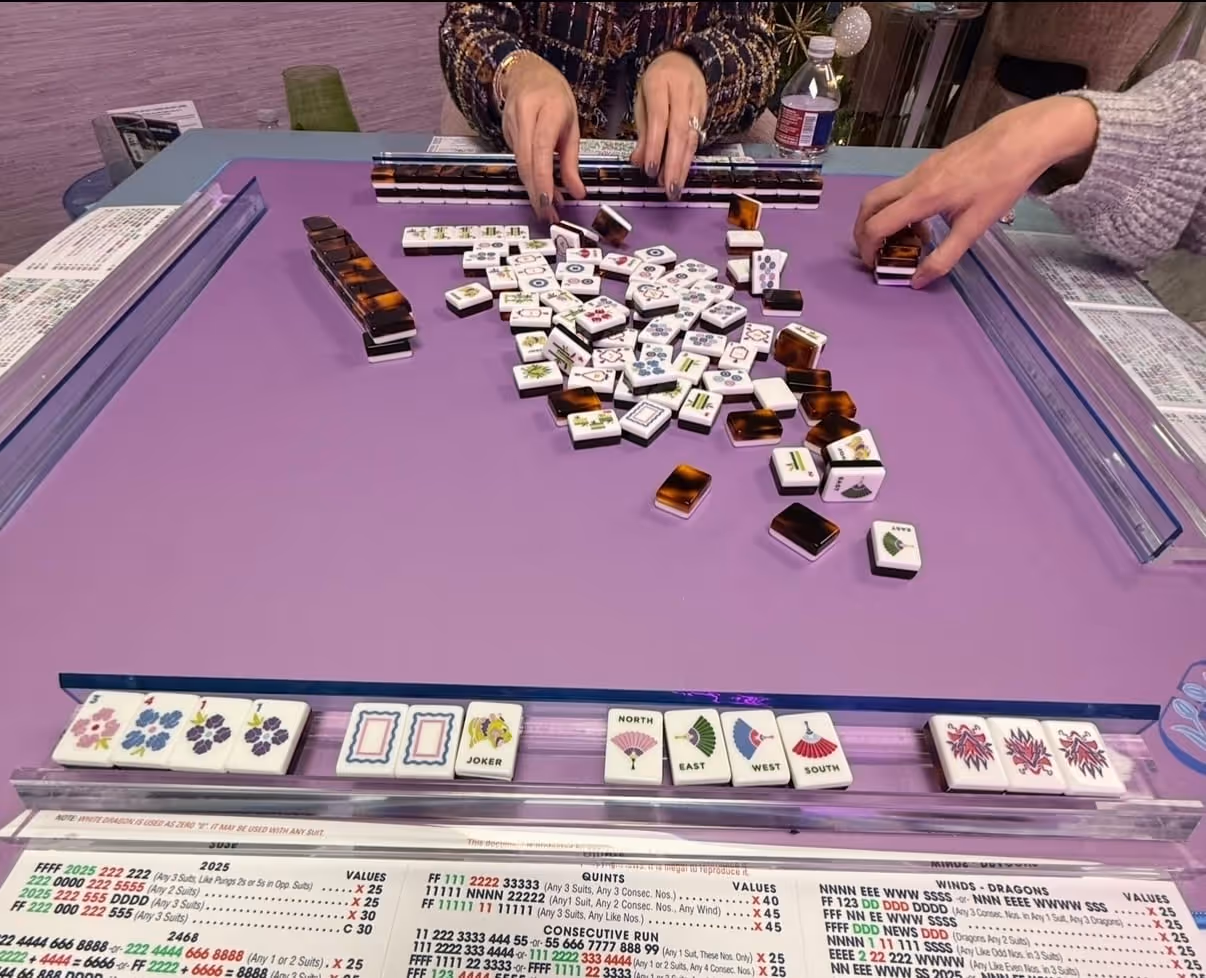 Mahjong tiles and racks laid out on a vibrant playing mat