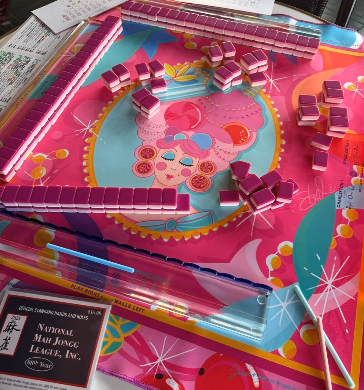 Colorful American mahjong tiles spread across the mat, seen from above