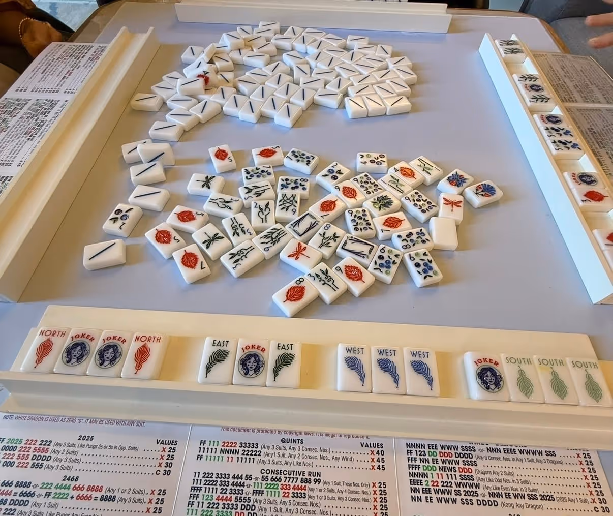 A close-up of mahjong tiles arranged along the racks mid-game