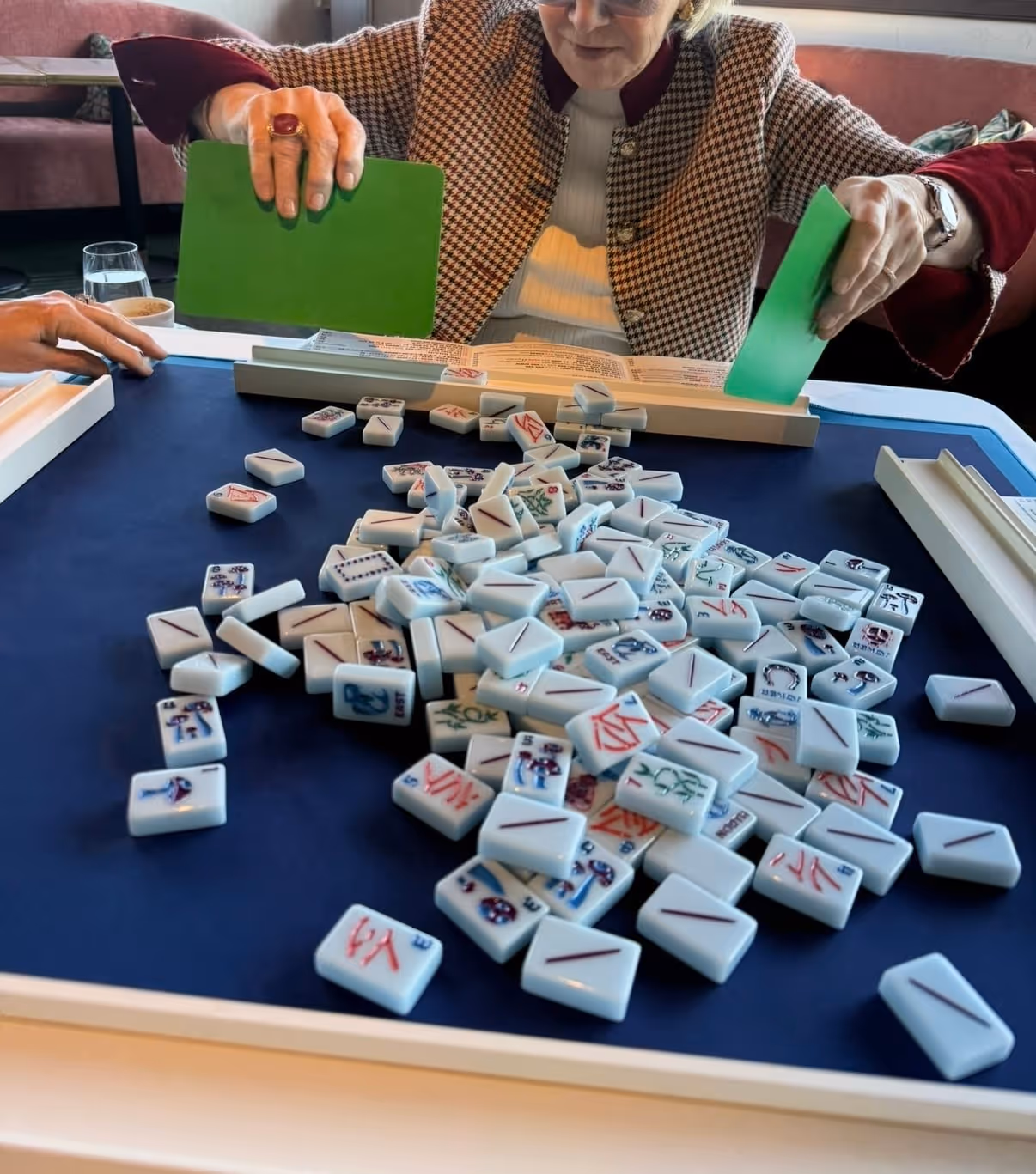 Hands washing the tiles — shuffling them face-down across the mat before a game begins