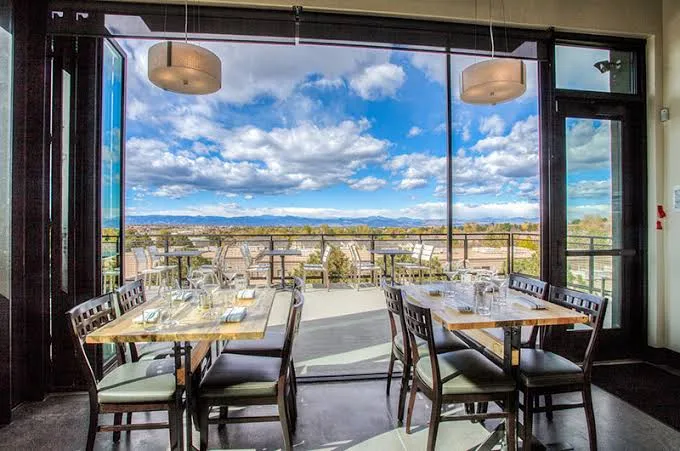 Inside Uncorked Wine Bar in Centennial, bright windows framing mountain views from the upstairs dining room